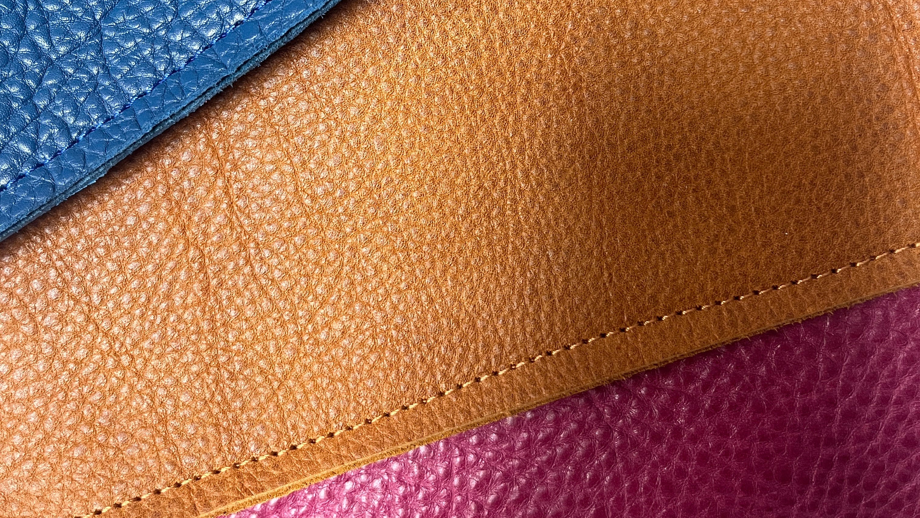 Close-up of blue, brown, and pink textured leather samples.